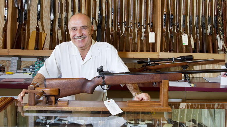 Smiling Gun Shop Owner Displaying a Rifle